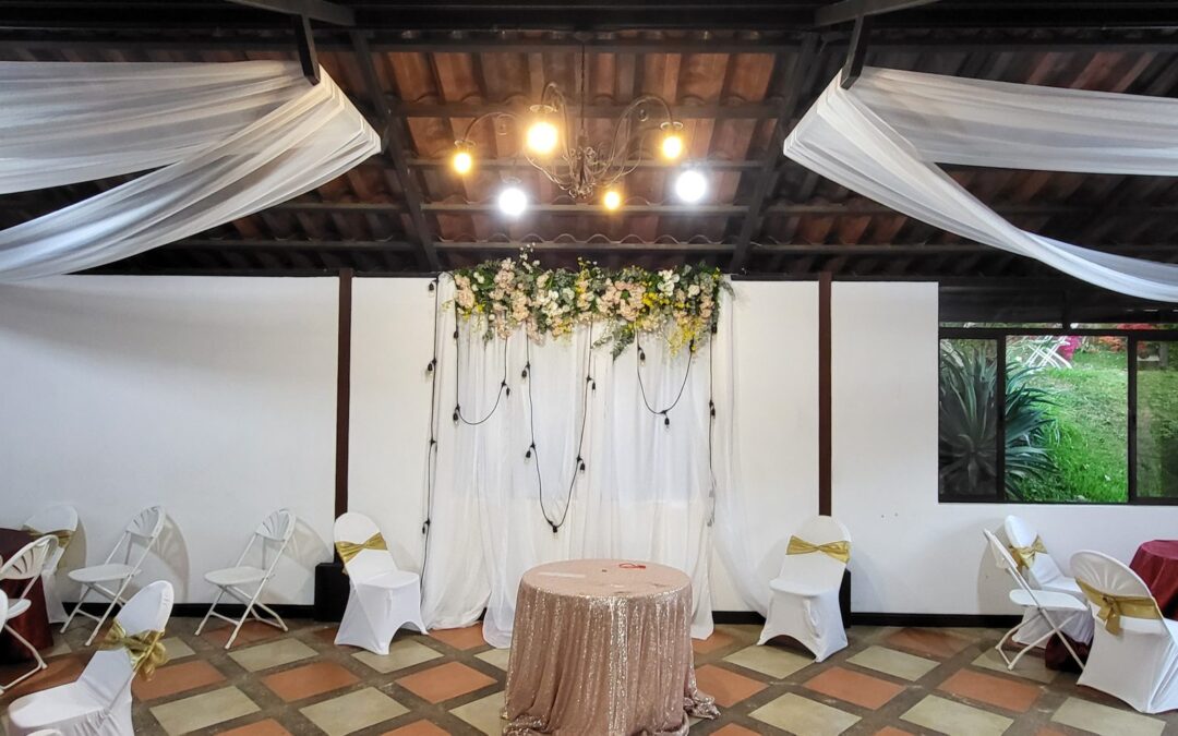 Salón decorado con telas blancas y arco floral